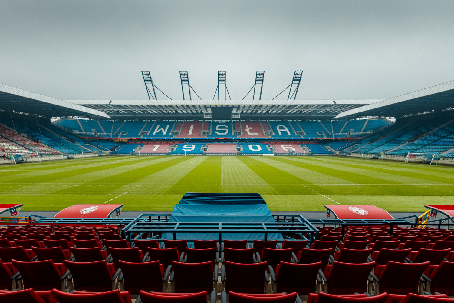 Pitch-level view across Wisła Krakow Stadium with red seating and WISŁA 1906 lettering